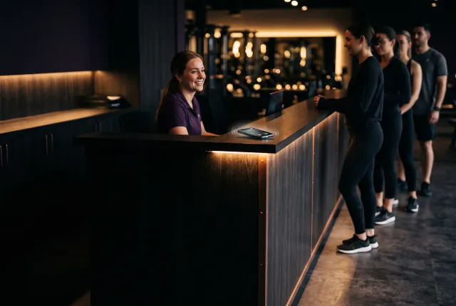 Crunch Fitness Schaumburg — a gym front desk with a line of members and a ringing phone on the counter