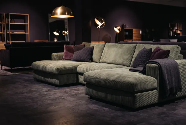 Sofa Co — a sage green corduroy sectional sofa styled in a warm furniture showroom
